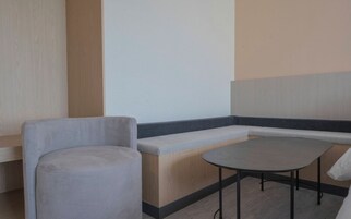 Una zona de estar con un banco y una mesa redonda, suelo de madera y una pared con panel vertical de madera.
