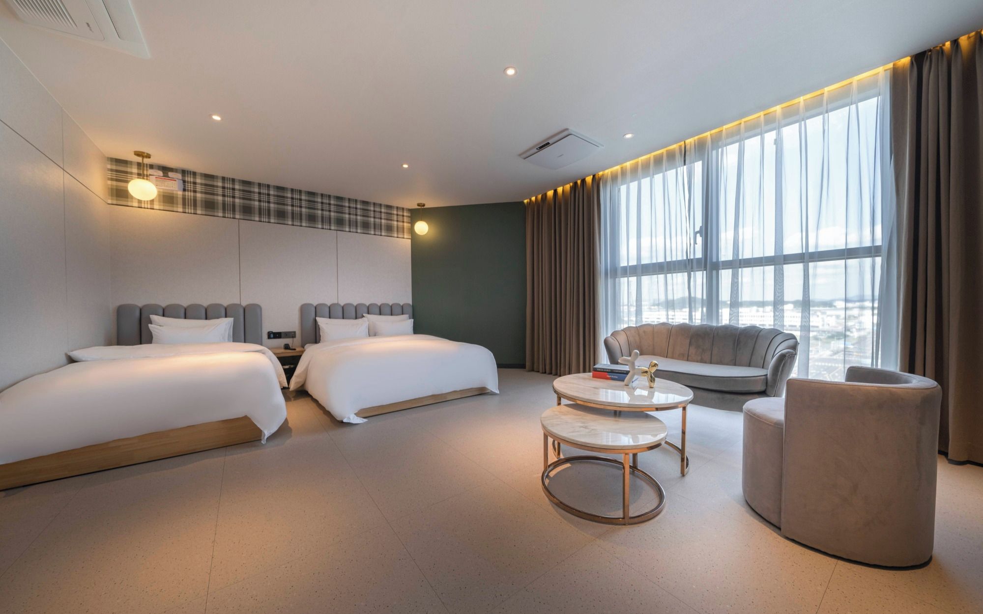 Habitación de hotel con dos camas, un sofá, una mesa de centro y vistas a la ciudad.
