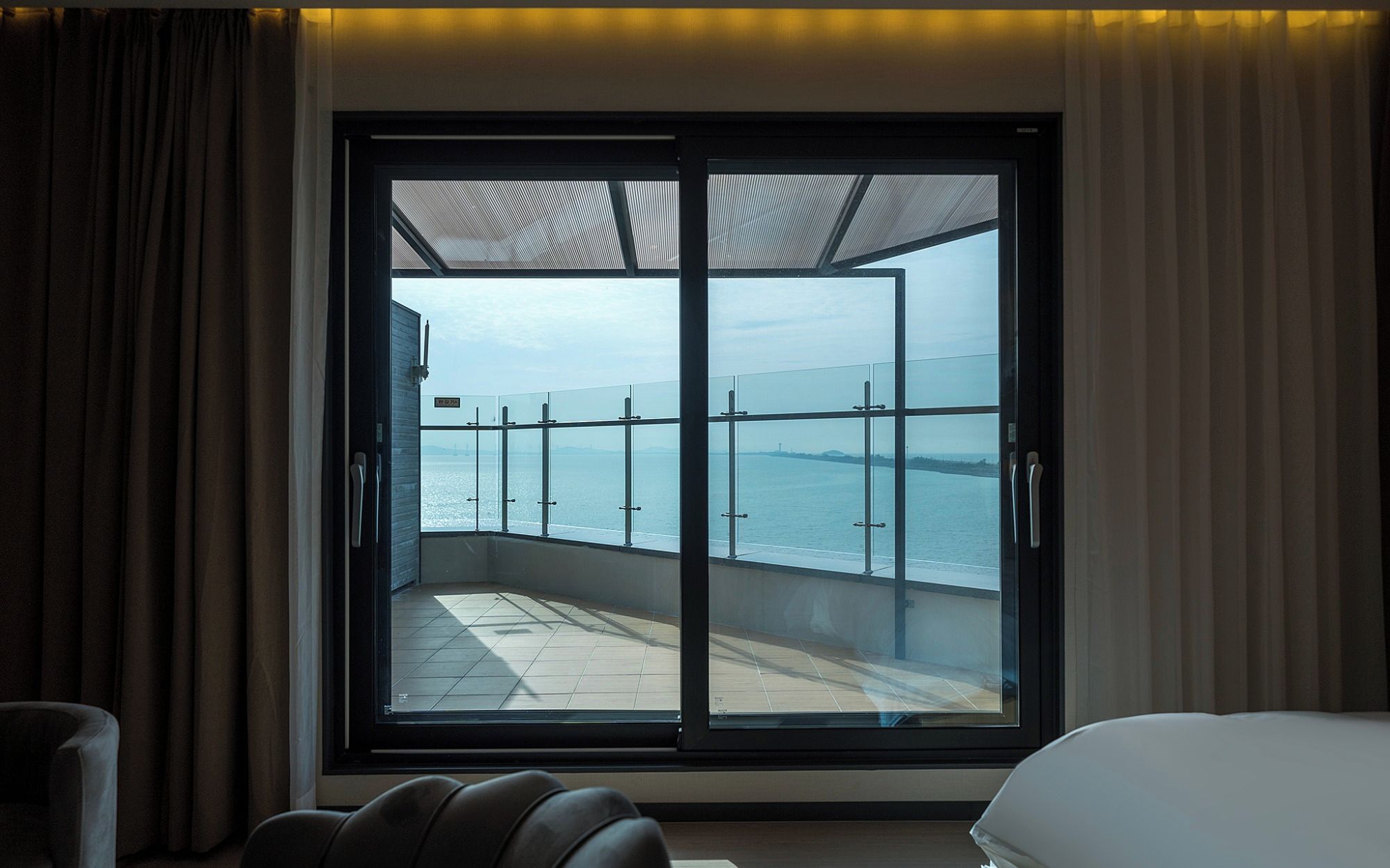Ein Hotelzimmer mit einer großen Schiebeglastür, die auf einen Balkon mit Meerblick führt.