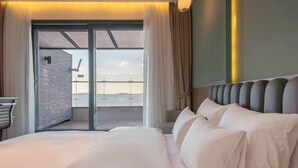 Una habitación de hotel con una cama grande, vistas a través de un ventanal y un diseño moderno.