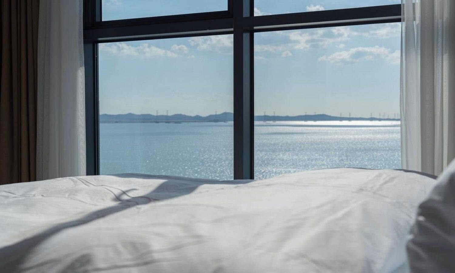 Cama com vista para um corpo de água calmo e terra distante.