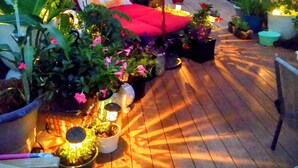 A wooden deck with a red sofa and a white canopy. There are potted plants and a small table with a lamp. - Lush Rooftop Terrace  City views A luxurious stay in  Central Downtown Area
 (Louisville)