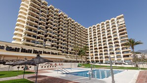 Un hotel grande con varios balcones, piscina y palmeras.