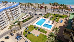 Ein Hotel mit Swimmingpool, Palmen und Blick auf den Strand.