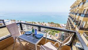 Ein Balkon mit Tisch für zwei Personen, mit Blick auf Strand und Meer.