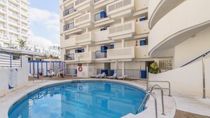 Une piscine à bord incurvé, entourée de murs blancs et de rampes bleues.