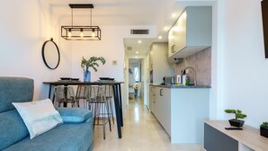Un salon moderne comprenant un canapé, une table à manger avec des chaises et un coin cuisine avec des placards et un évier.