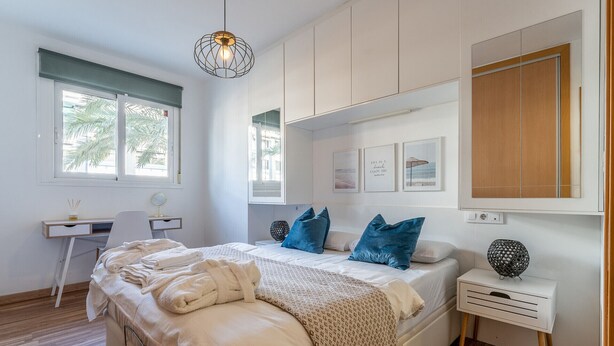 Ein Schlafzimmer mit einem Bett, Nachttischen, einem Schreibtisch und einem großen Fenster.