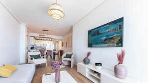 A modern living room with a sofa, chairs, a dining area, and a kitchen in the background. - Superb Location Beachfront , 3 bed with terrace REF044 (Fuengirola)
