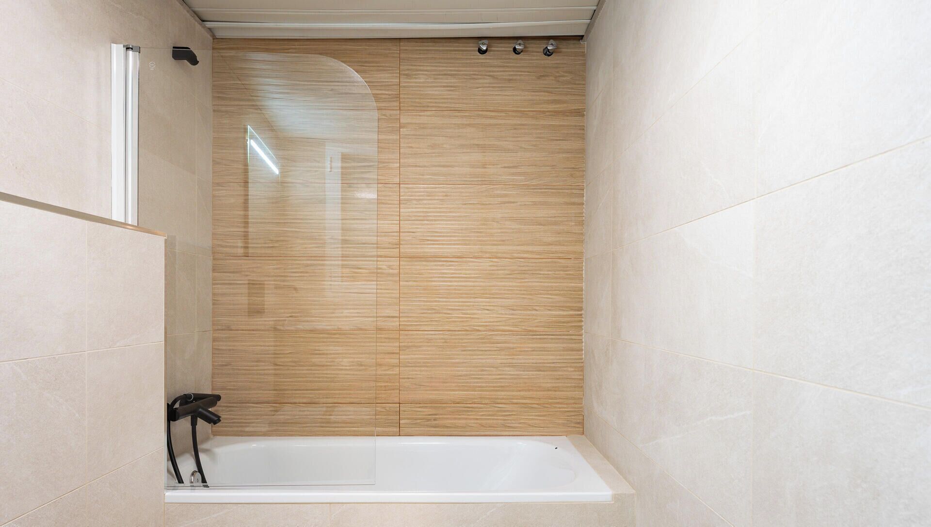 A modern bathroom with a bathtub, a shower enclosure, and a towel rack.