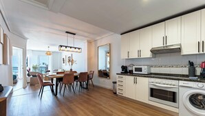 A modern kitchen with white cabinets, a built-in oven, microwave, and washing machine. - Superb Location Beachfront , 3 bed with terrace REF044 (Fuengirola)