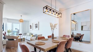 A modern dining area with a wooden table, woven placemats, and pendant lighting. - Superb Location Beachfront , 3 bed with terrace REF044 (Fuengirola)