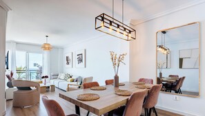 A modern dining area with a wooden table, woven placemats, and pendant lighting.
