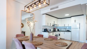 A modern kitchen with white cabinets, a built-in oven, and a refrigerator.
