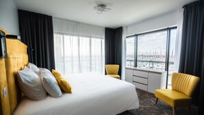 A hotel room with a large bed, two chairs, a desk, and a view of a marina. - Hôtel Barracuda & Spa, Centre Port, pieds dans l'eau, vue mer (Brest)