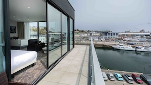 A modern hotel room with a large balcony, a bed, a sofa, and a view of a marina with boats and buildings. - Hôtel Barracuda & Spa, Centre Port, pieds dans l'eau, vue mer (Brest)