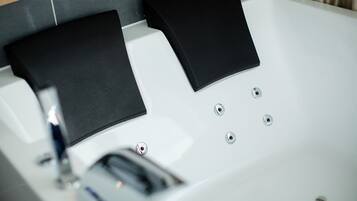 A modern bathtub with black mats and a chrome faucet.