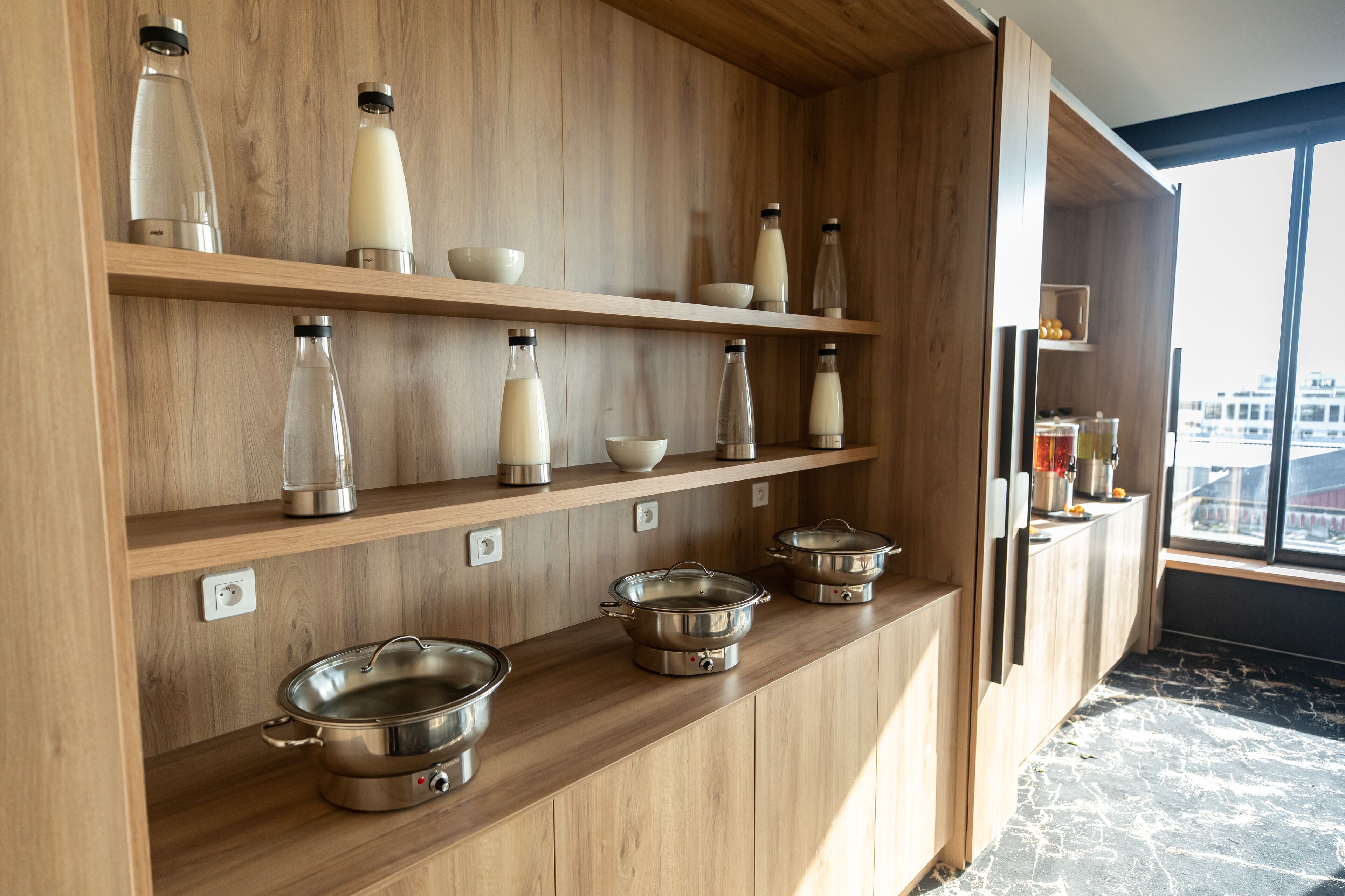 Una cocina con repisas de madera que sostienen diversos utensilios de cocina y botellas.