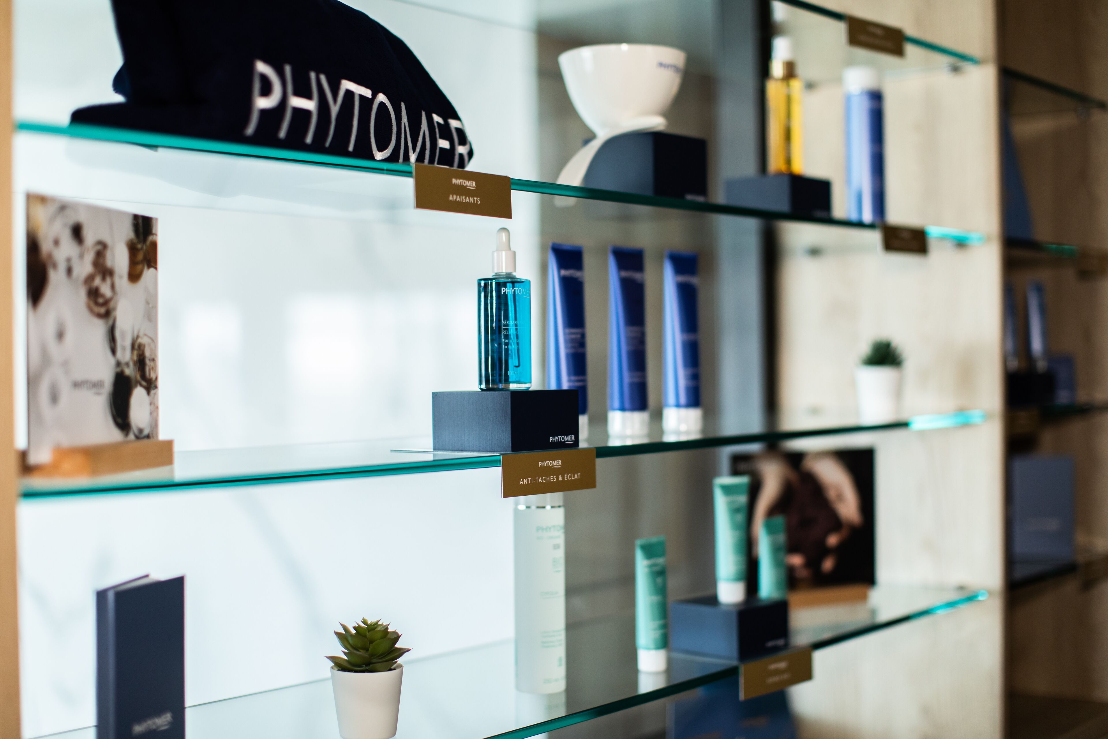 A display of skincare products on glass shelves with labels indicating categories like 'PHYTOMER' and 'ANTI-ITCHES & ECTH'.