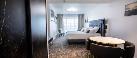 A hotel room with a bed, a round table with chairs, a desk, and a chair.
