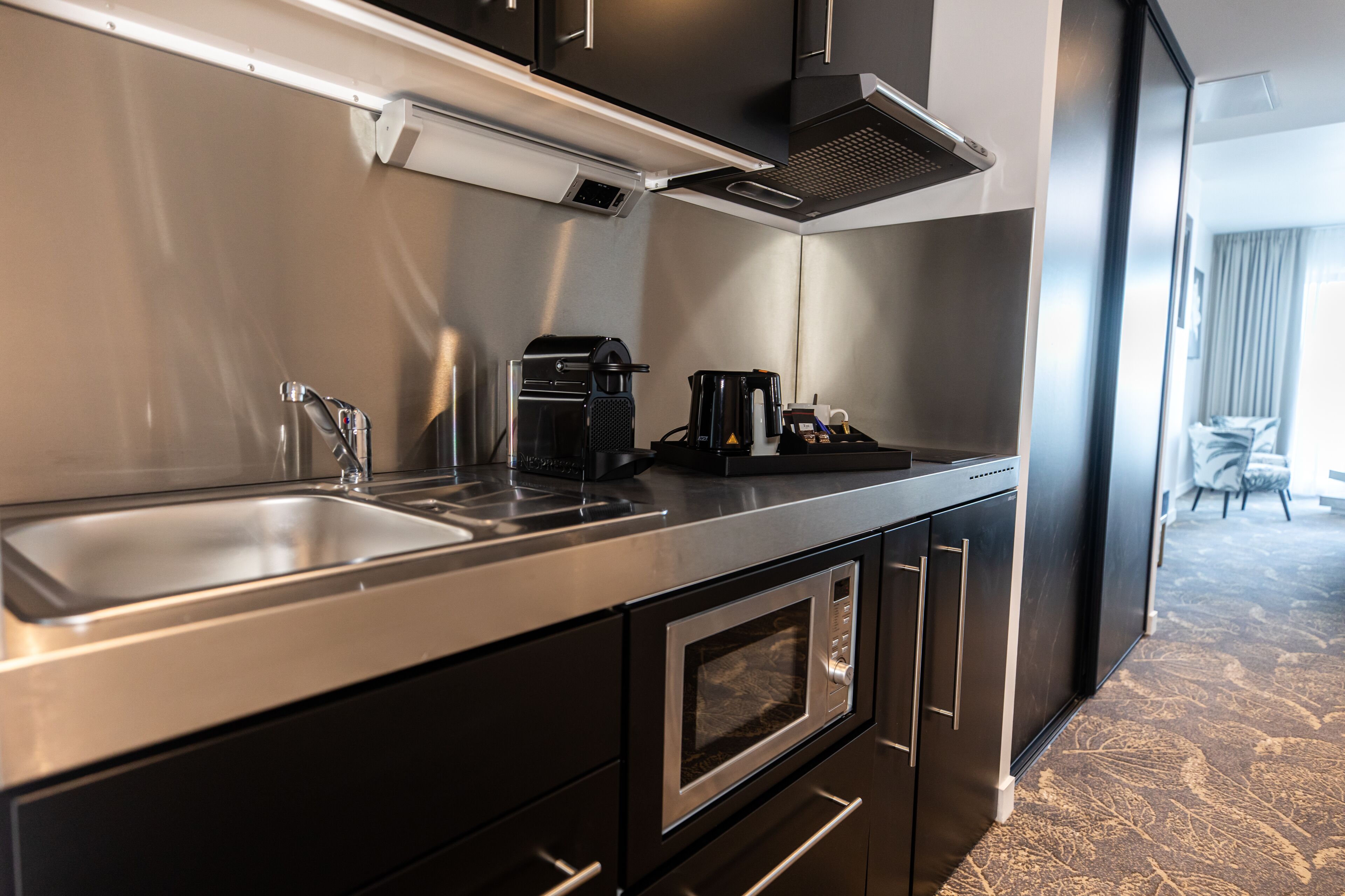 Una cucina moderna con lavello in acciaio inox, macchina da caffè e forno a microonde.