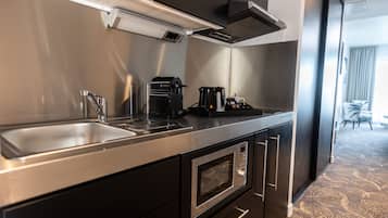 Una cocina moderna con un lavamanos de acero inoxidable, una cafetera y un microondas.