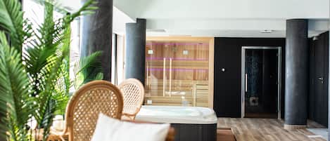 A modern spa area with a hot tub, wicker chairs, and a wooden reception desk.