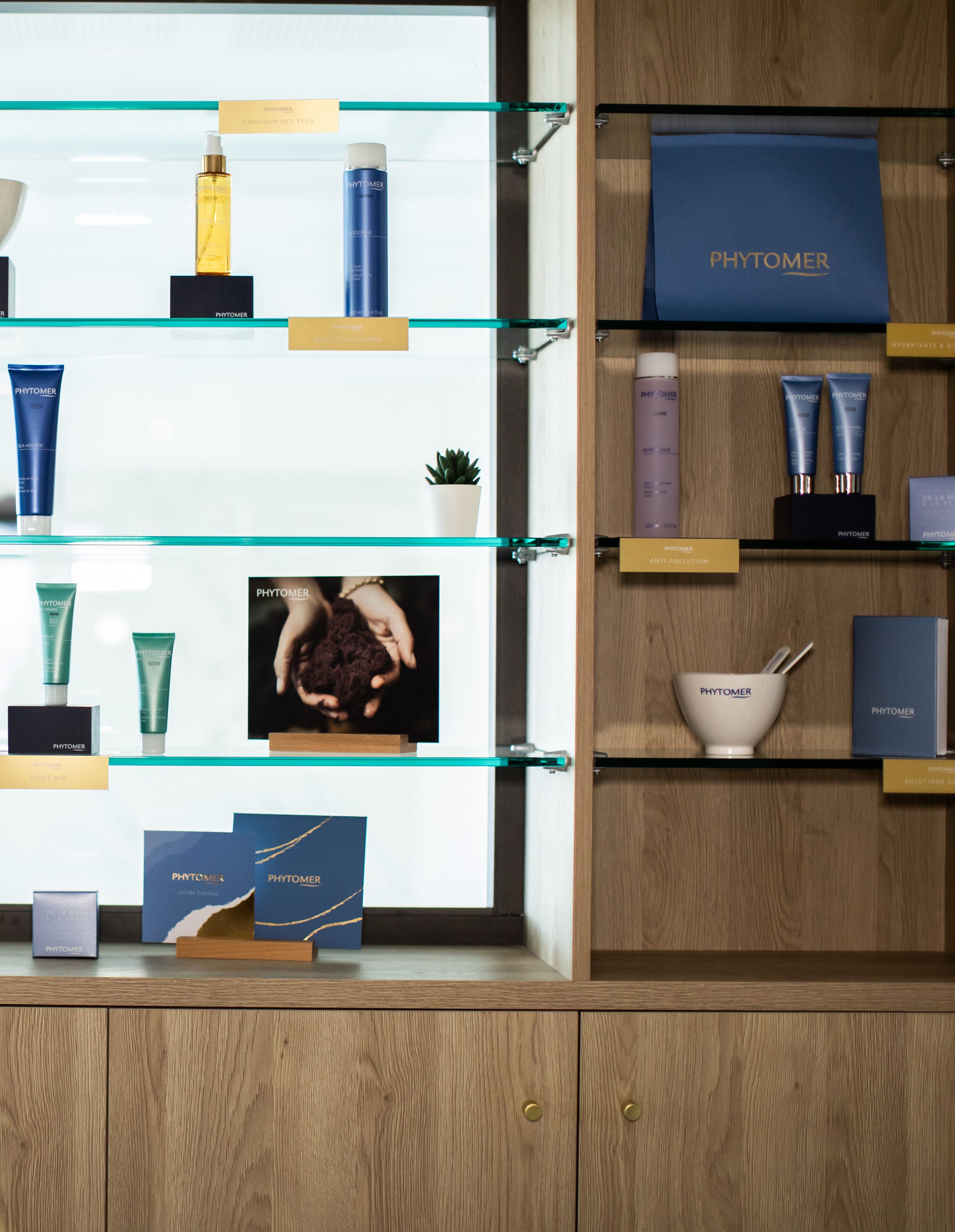 A display of Phytomer skincare products on shelves with a wooden cabinet in the background.