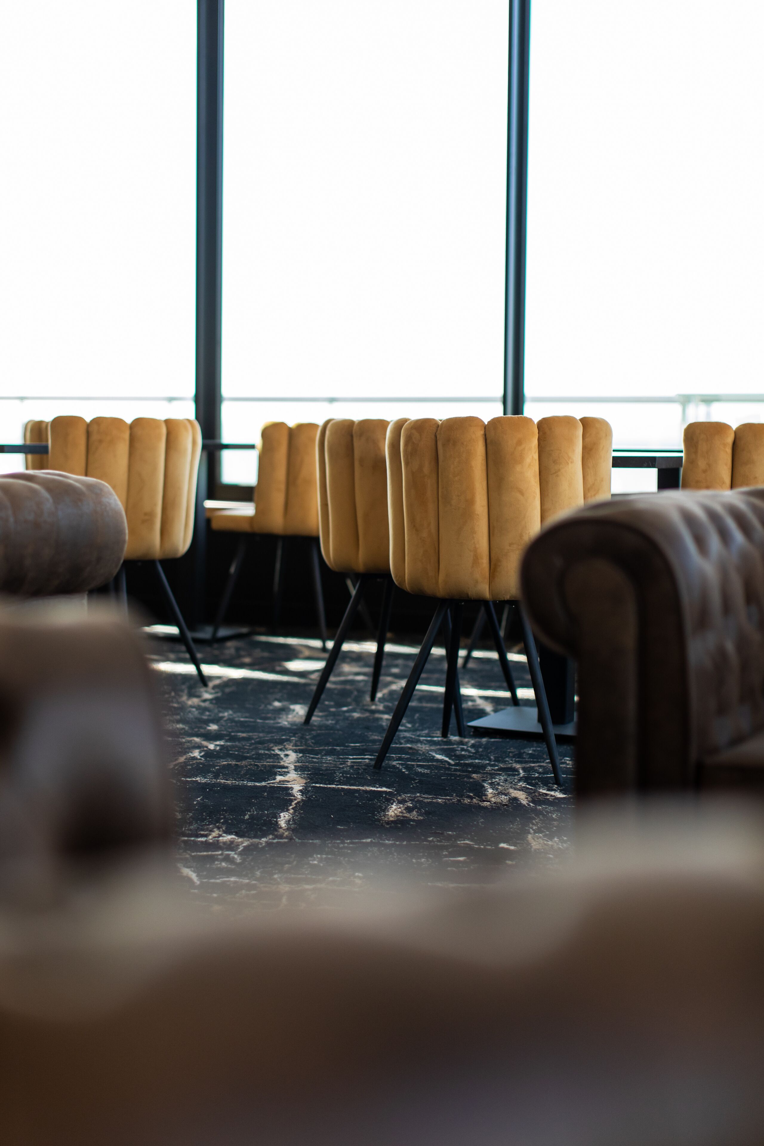 A row of yellow chairs with black legs in a room with large windows.