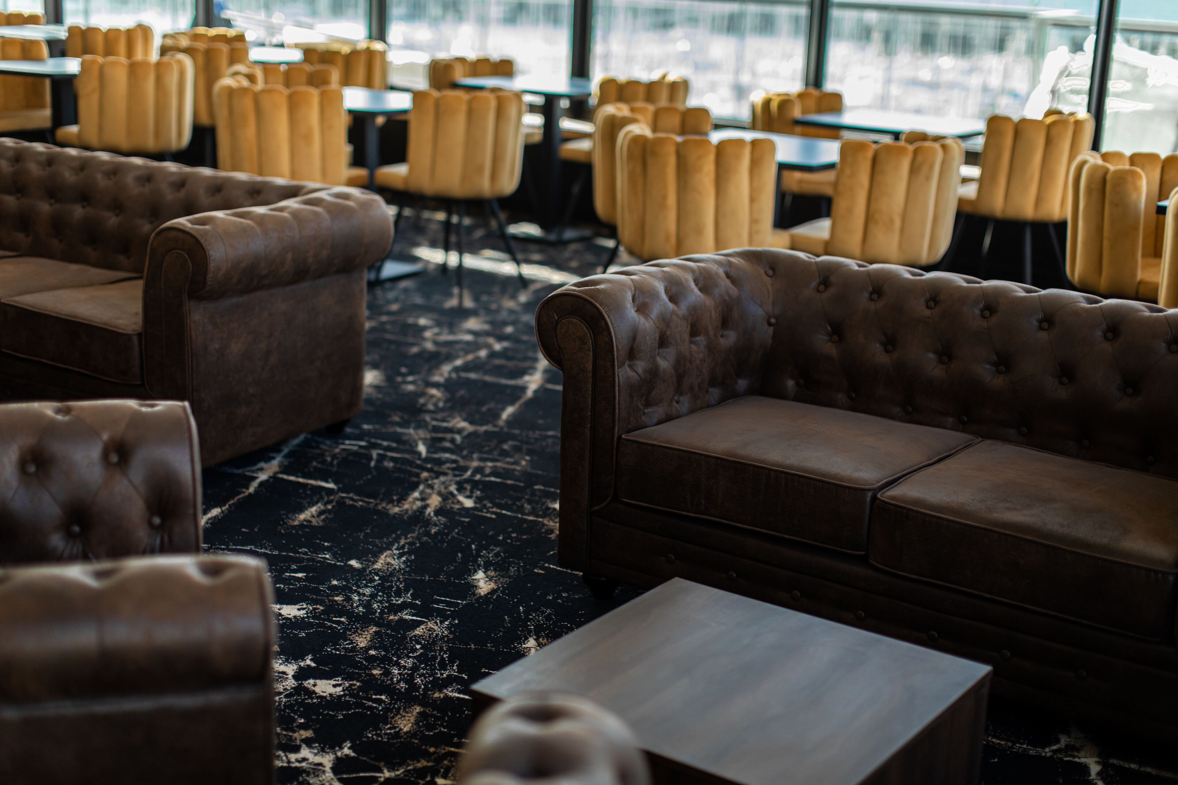 A restaurant with leather sofas and tables, a marble floor, and large windows.