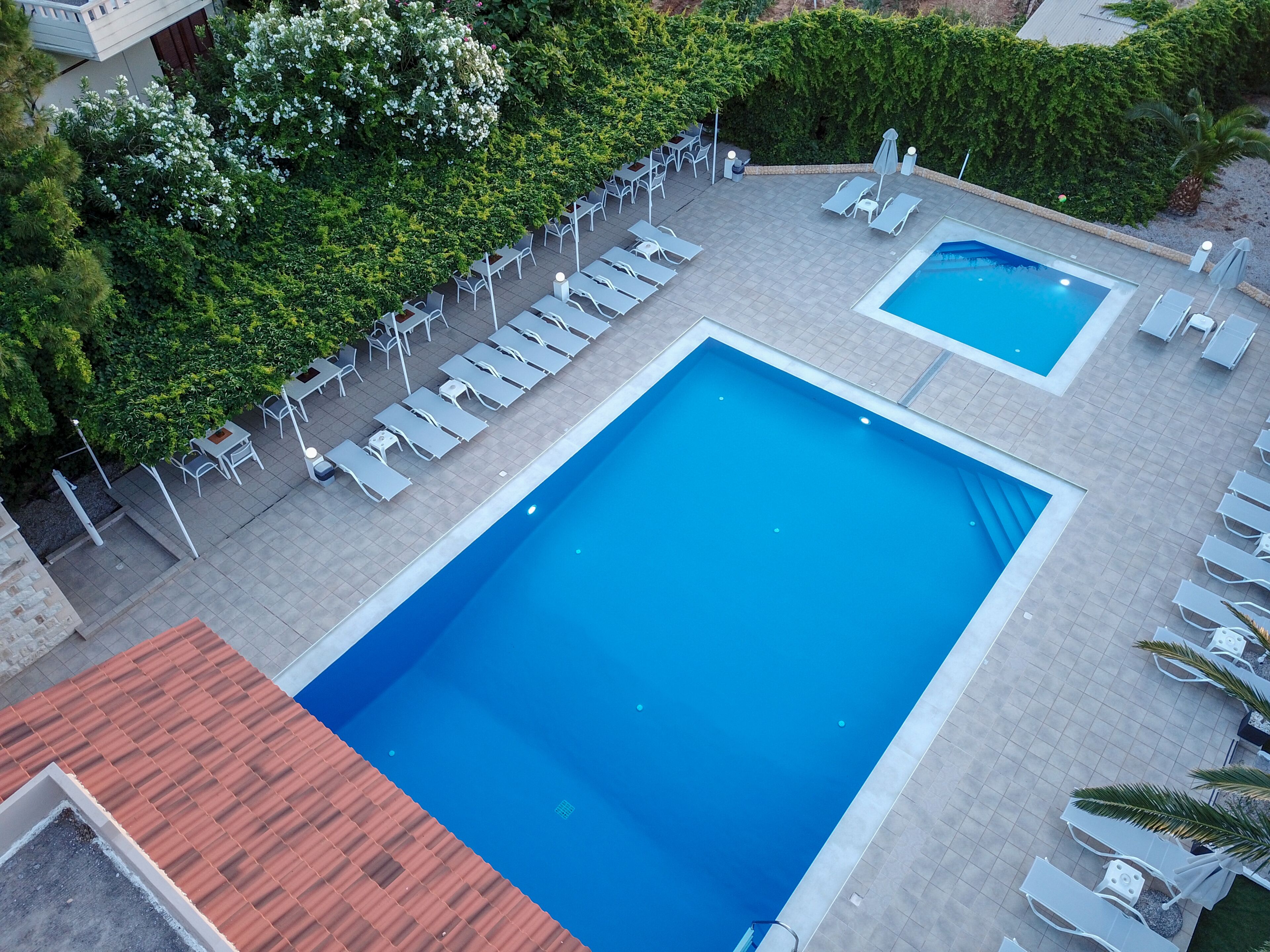 Et tagområde med swimmingpools, liggestole og en omgivende have.