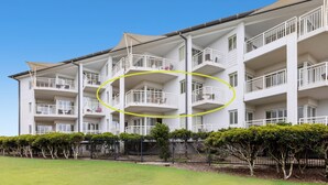 Un hôtel à plusieurs étages, doté de balcons, d’un toit plat et d’une pelouse parfaitement entretenue.