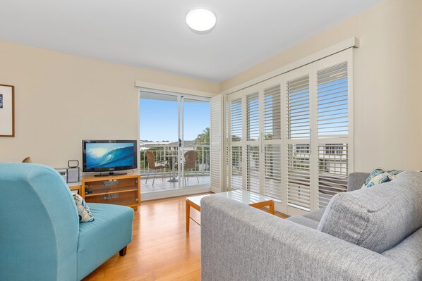 Relax in this stylish living room with a large flat-screen TV, sofa, and armchair, offering a comfortable space to unwind.