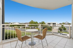 Enjoy the serene view of the neighborhood from this balcony with a round table and two chairs.