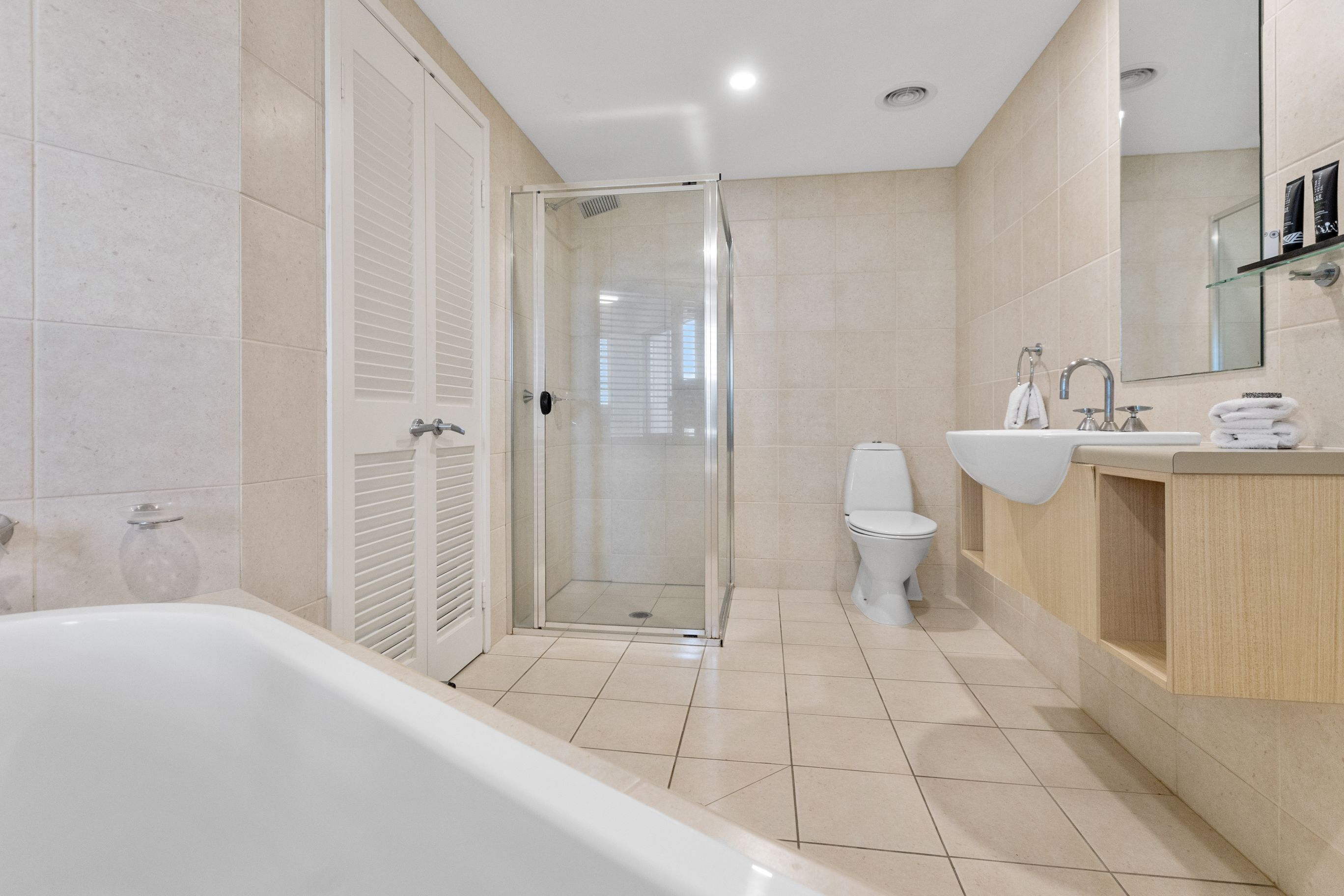 A modern bathroom with a glass-enclosed shower, a white bathtub, a sink, and a toilet.
