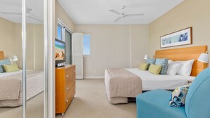 A hotel room with a bed, a dresser, a television, and a ceiling fan. - The Pool Resort Kingscliff - 1 BR Spa Suite (7220) - Holiday Management Co. (Tweed)