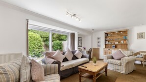 A living room with a sofa, armchairs, a wooden coffee table, and a bookshelf. - Loughrigg -  a bungalow in the centre of Rock with parking (Rock)