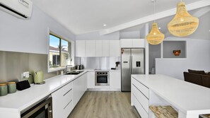 A modern kitchen with white cabinetry, stainless steel appliances, and a large window.