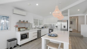 A modern kitchen with white cabinetry, a built-in oven, a dishwasher, and a large island with a sink.
