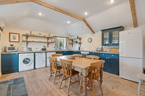 Une cuisine équipée d’une table à manger, de chaises, d’un lave-linge, d’un lave-vaisselle et d’un réfrigérateur.
