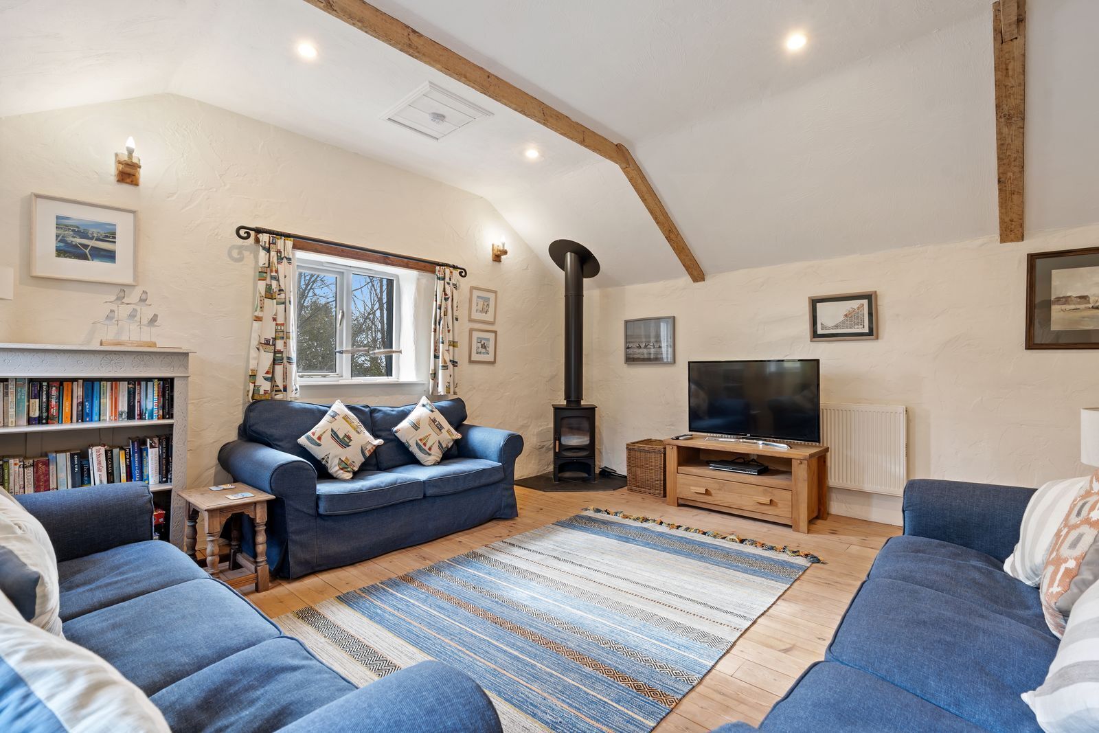 A cozy living room with a sofa, a television, a bookshelf, and a fireplace.