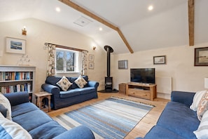A cozy living room with a sofa, a television, a bookshelf, and a fireplace.