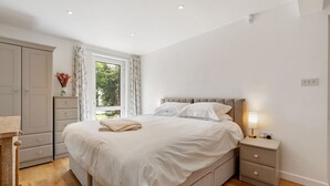 A bedroom with a bed, nightstand, dresser, and window with curtains. - Pen-Wethers -  Holiday Home that sleeps 8 guests  in 4 bedrooms (Rock)