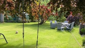 A well-maintained garden with a swing set, a small table with chairs, and a lawn. - Newly Refurbished, old Bull Pen cottage near Lewes East Sussex (Barcombe)
