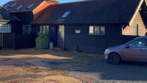 A two-story building with a dark exterior, a sloped roof, and a small garden area. - Newly Refurbished, old Bull Pen cottage near Lewes East Sussex (Barcombe)