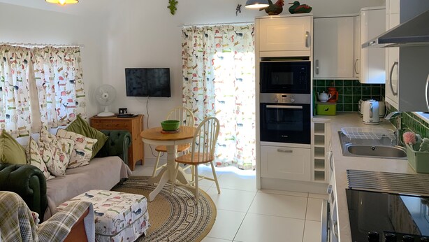 A cozy living room with a sofa, a dining table, and a kitchen area with appliances. - Newly Refurbished, old Bull Pen cottage near Lewes East Sussex (Barcombe)
