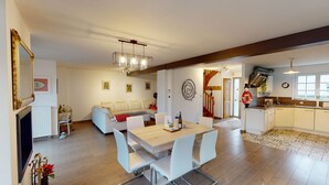 Un espacio habitable moderno con comedor, sofá, cocina y una escalera.