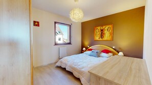 Un dormitorio con cama, mesita de noche, lámpara y una obra de arte en la pared.