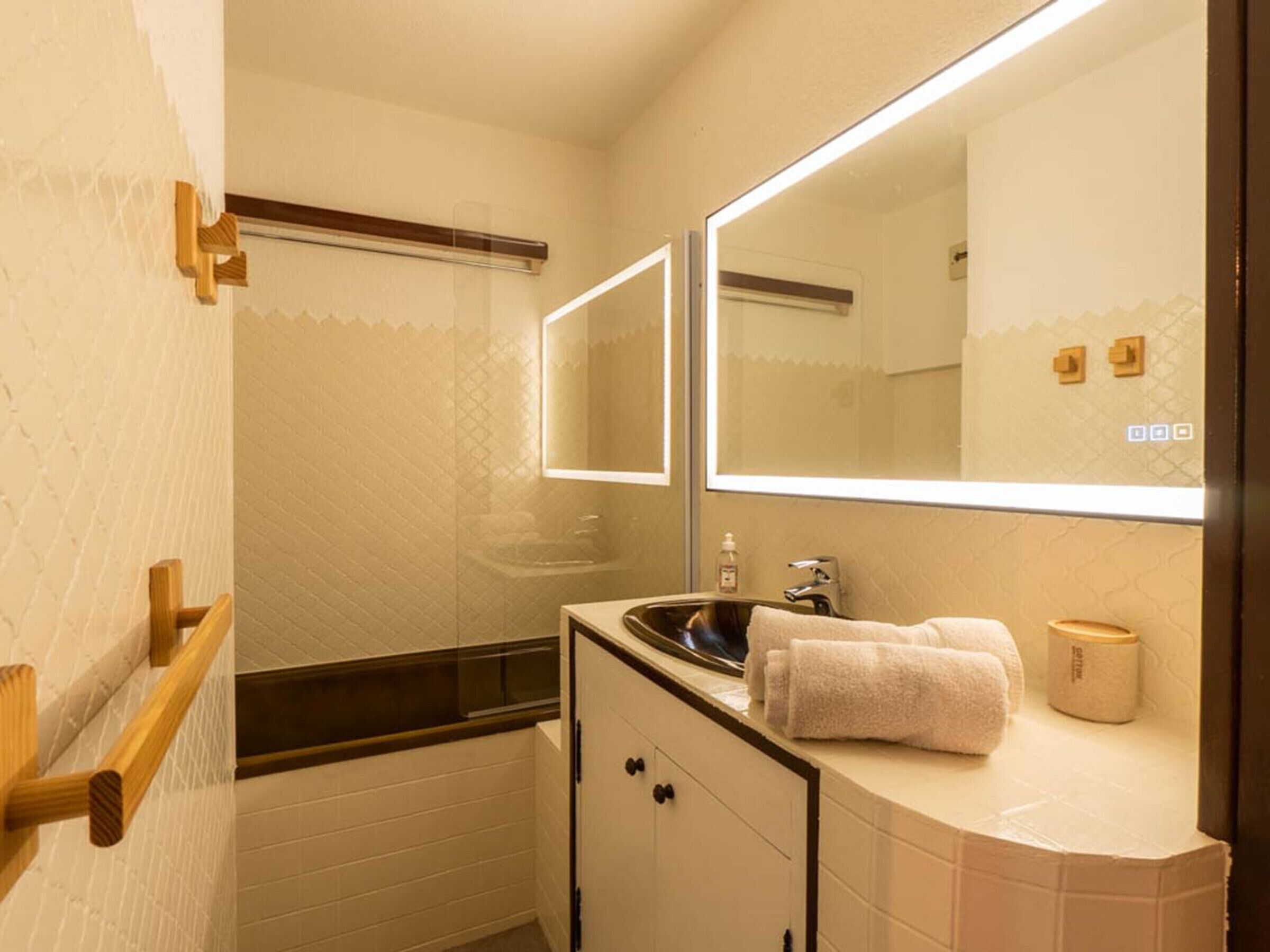 A bathroom with a sink, mirror, towel, and a wooden rack.