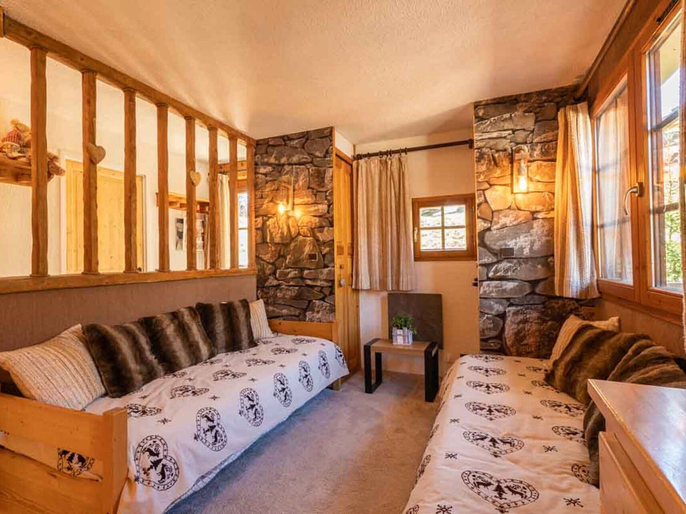 A cozy room with two beds, stone walls, and a fireplace.